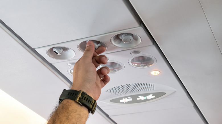 Person adjusting plane air vent