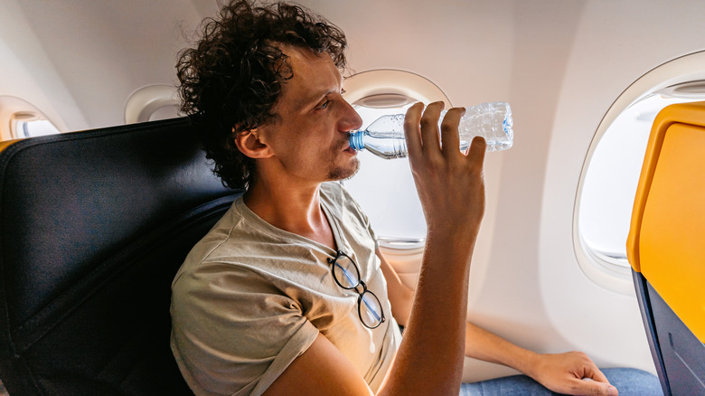 Man drinking water on plane