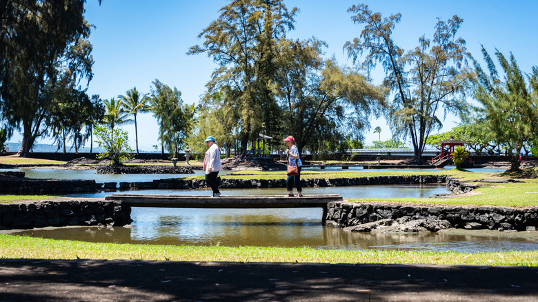 Two visitors cross a bridge in Liliuokalani Gardens