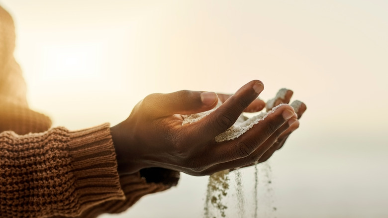 hands with sand slipping through