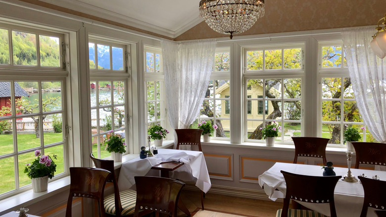 A formal dining room surrounded by windows overlooking water and mountains