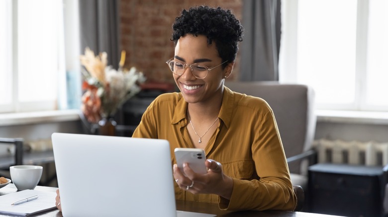 Woman looking at her phone and laptop