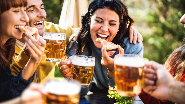 Friends eating pizza with beer