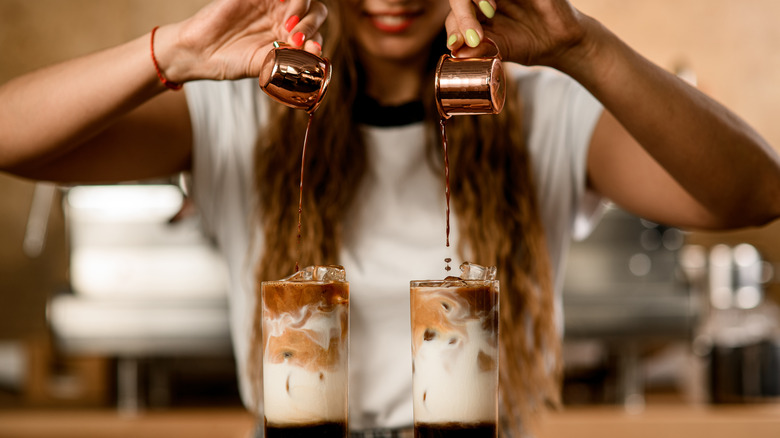 woman pouring espresso into iced coffee glasses