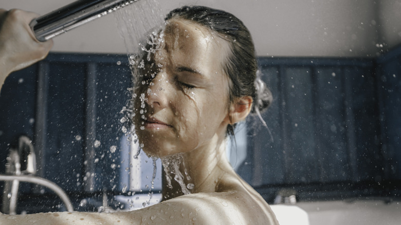 Young woman using handheld shower