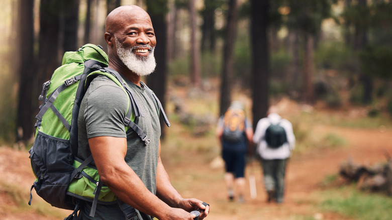 Bearded man with backpack smiles in woods