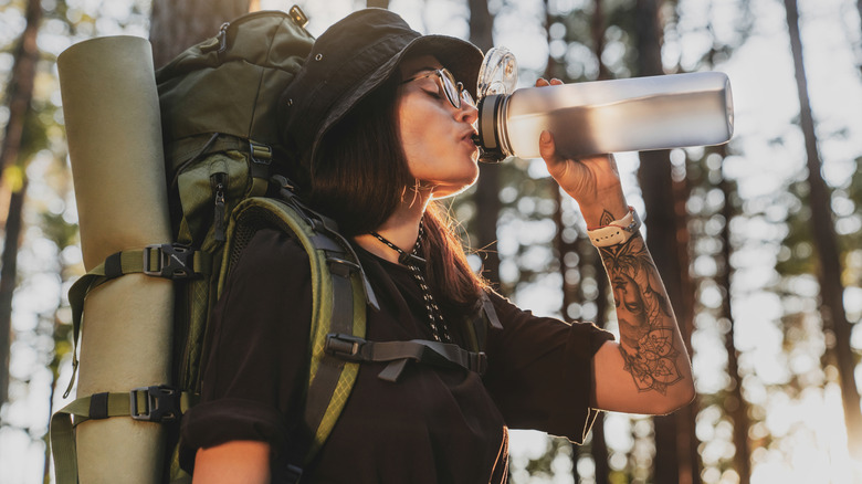 Hiker with heavy backpack swigs from bottle of water