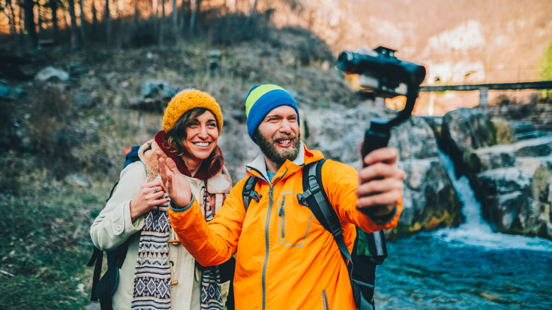 A man and woman pose for a selfie in the woods