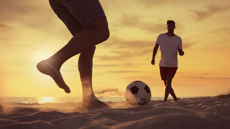 People playing soccer on beach