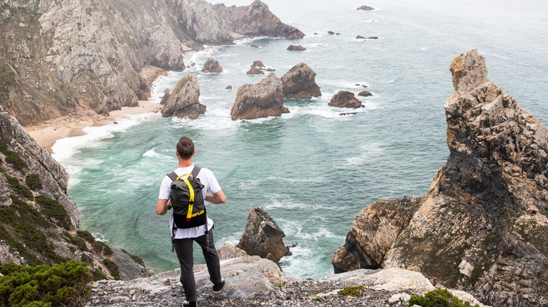 hiker on cliff above ocean