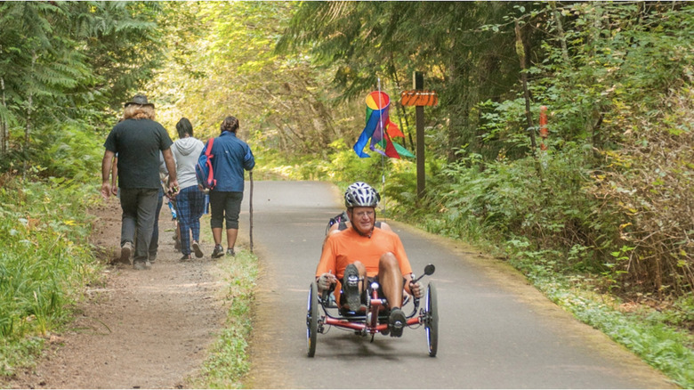 Man on a recumbent bicycle with family walking