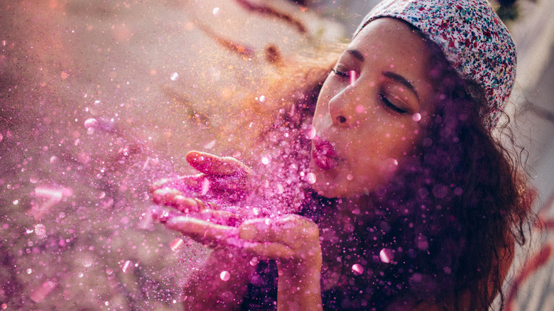 A woman blowing glitter