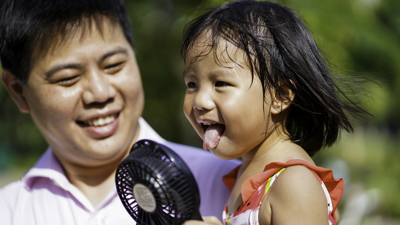 father and child with fan