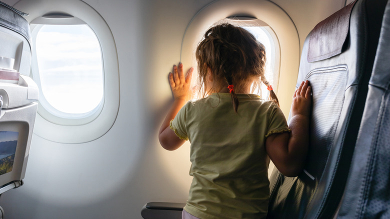 A small child looks out of an airplane window.