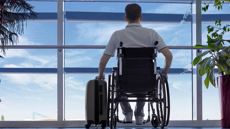 Man in wheelchair with luggage at airport