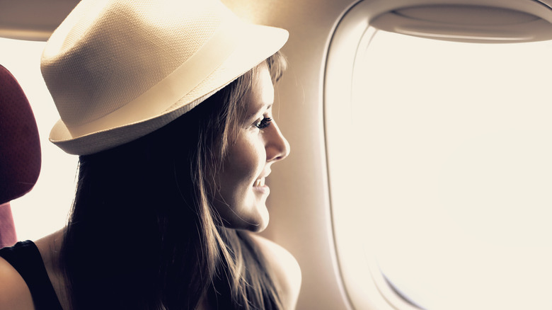 young woman looking out airplane window