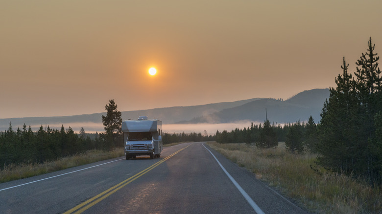 An RV on a road in Yellowstone National Park at sunrise