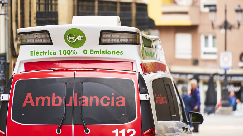 An ambulance labeled in Spanish is parked in the street