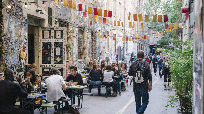 Young people sip on coffee in art-lined alley in Berlin