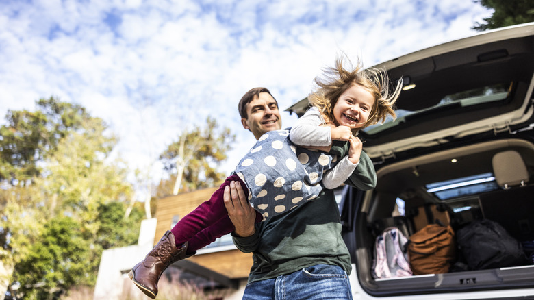 father lifting daughter by car