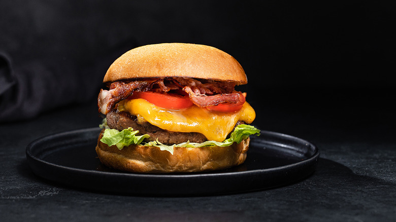 An enormous burger is displayed in a dark setting