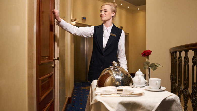 Hotel employee knocking on door with cart of room service