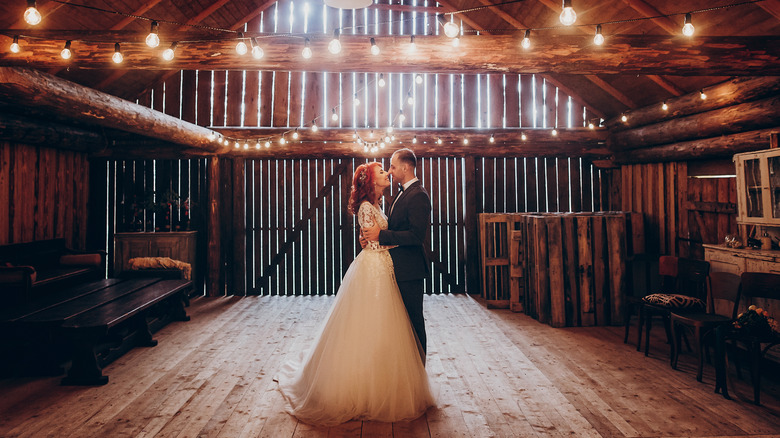 newlyweds in barn standing closely