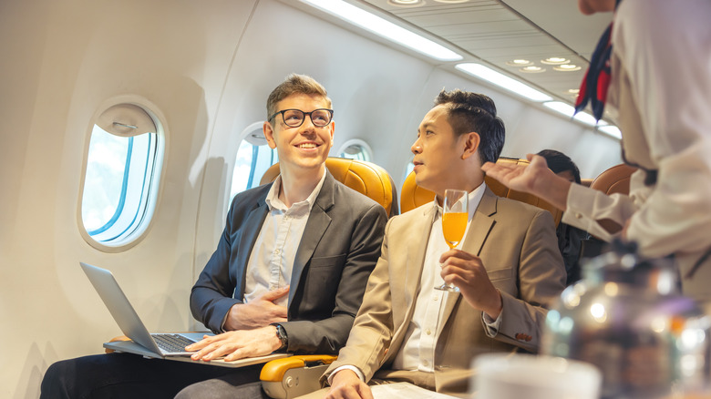 man ordering drink on plane