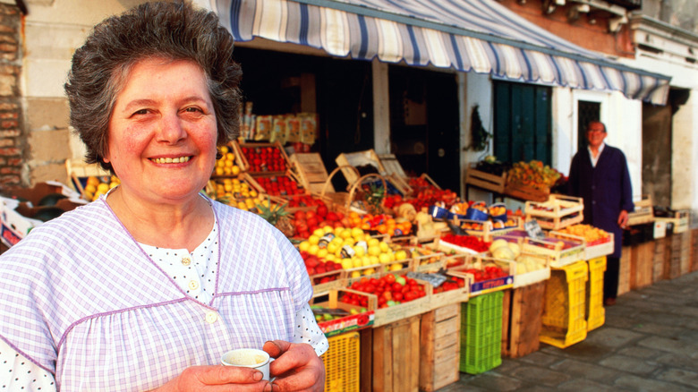 Smiling woman with espresso near shop