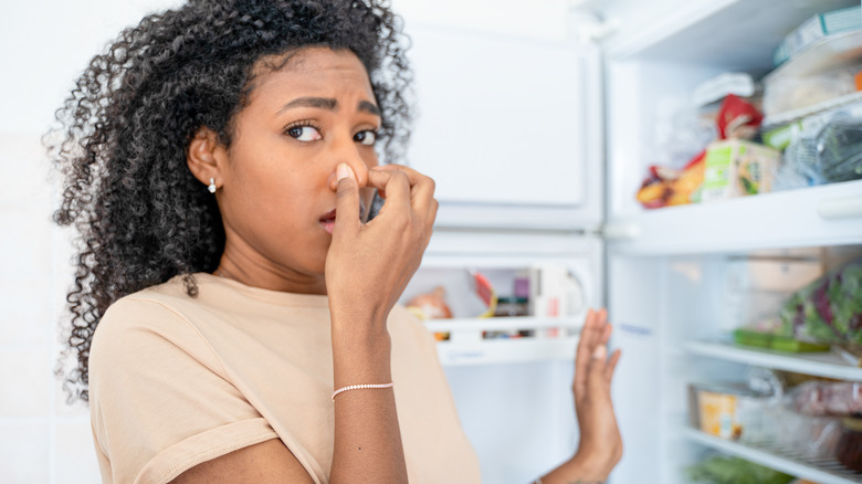 Woman pinching nose at fridge