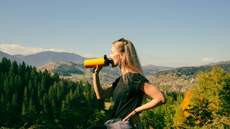 Woman drinking water in mountains