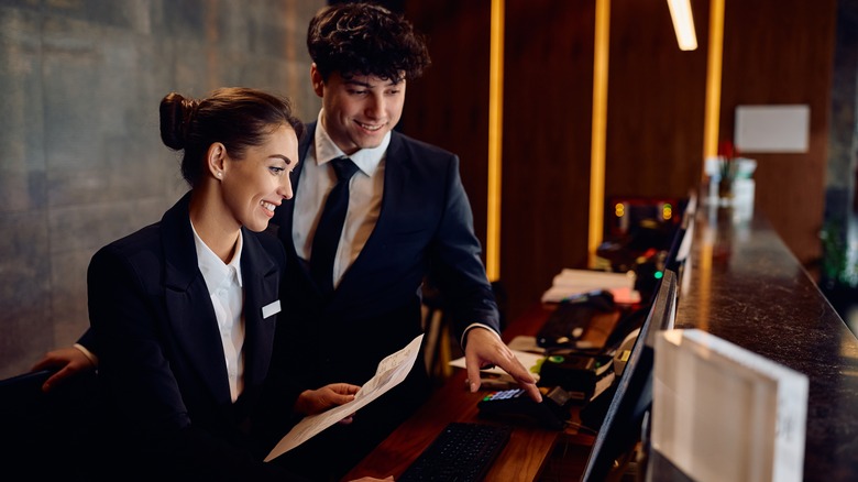 Two smiling hotel receptionists working