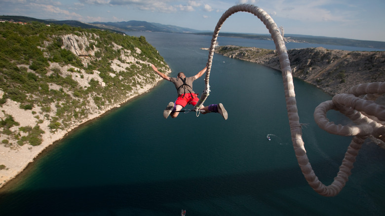 A man bungee jumps high above the water