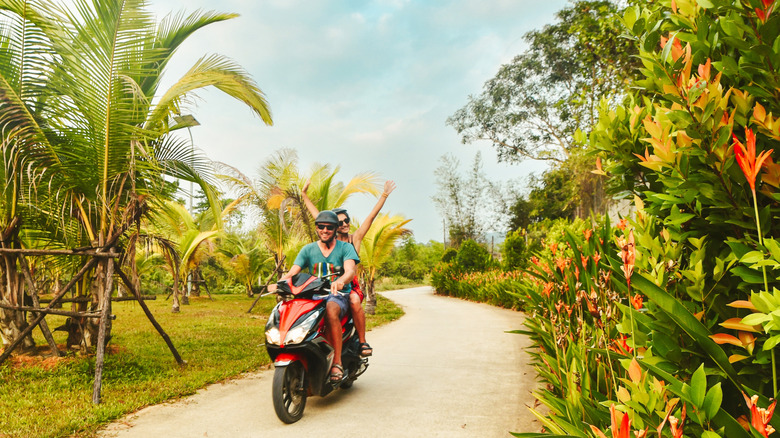 A couple cruise down a road in Vietnam in a motorbike