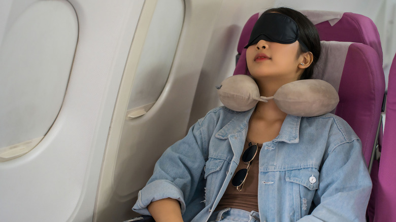 Woman sleeping on plane itch eye mask and neck pillow