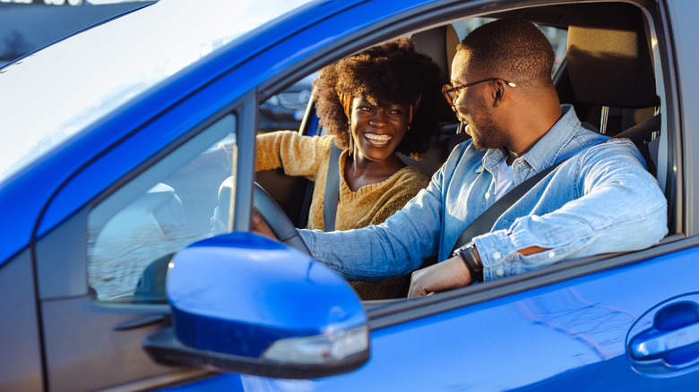 Traveling couple sitting in a blue car