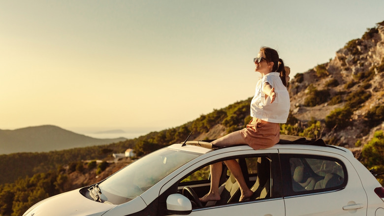 Traveler sitting on roof of rental car