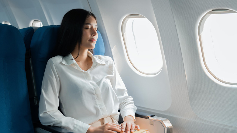 A woman is sleeping on a plane.