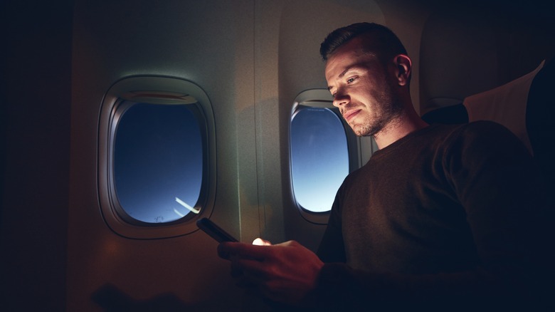 Traveler using smartphone on airplane