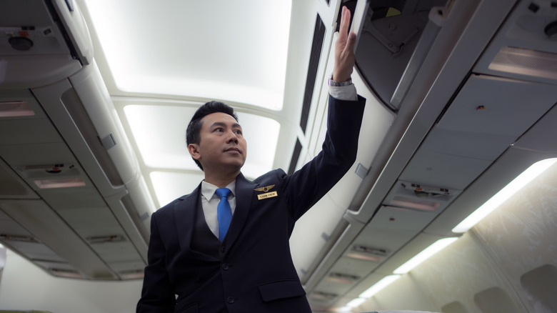 Flight attendant closing overhead compartment