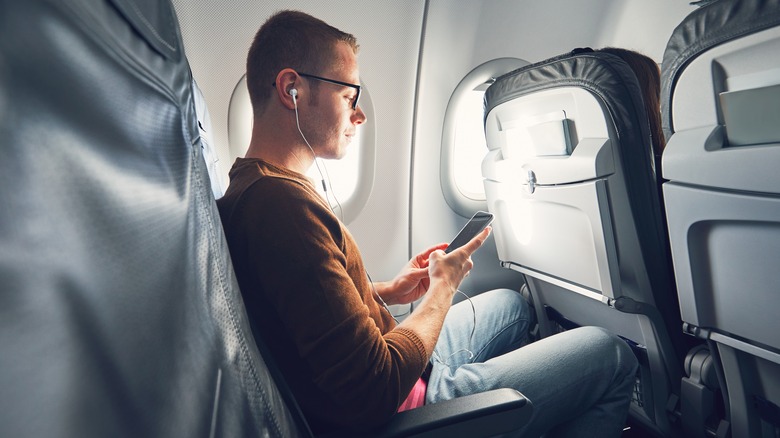 man on plane holding phone