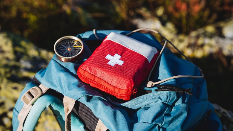 First aid kit and compass atop backpack