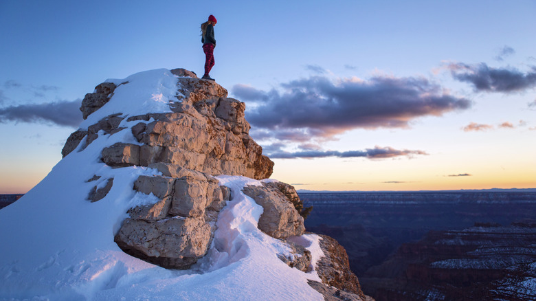 Female hiker standing on a snowy ledge at the Grand Canyon's North Rim