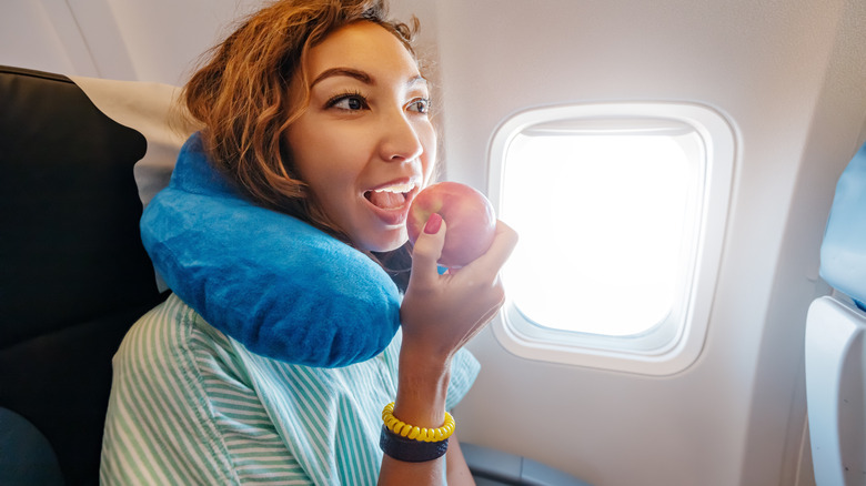 An airplane traveler bites into an apple.