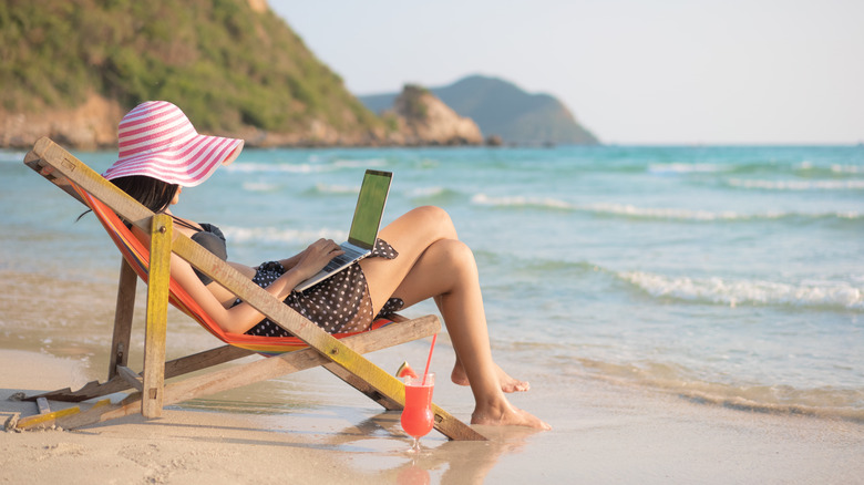 woman working with computer on beach