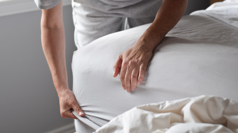 man removing sheet from bed