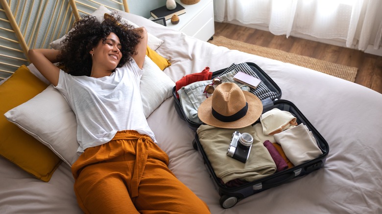 woman lying in bed with suitcase