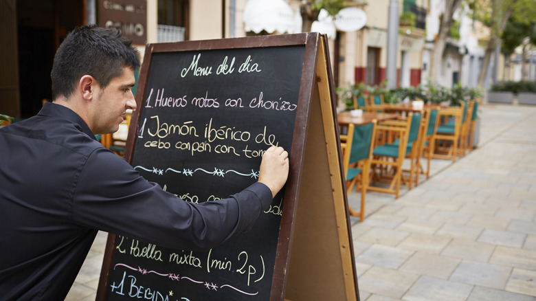 Waiter writing menu on chalkboard