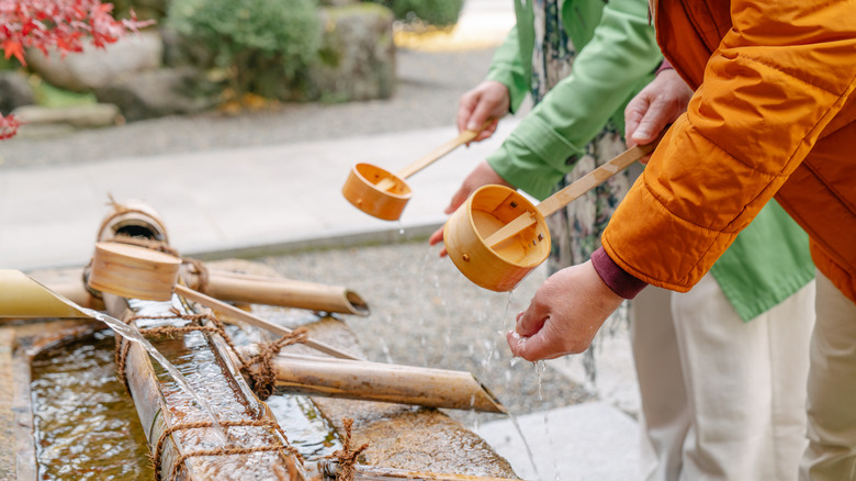 visitors using chozuya at japanese shrine