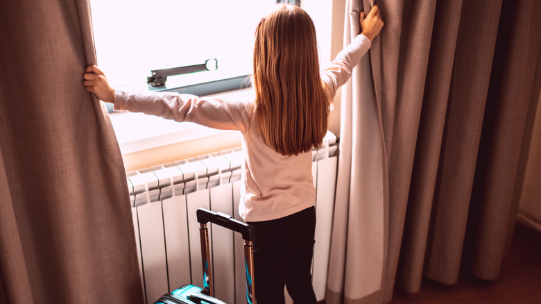 Girl opening hotel room curtain